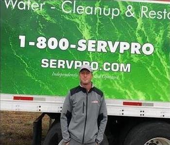 Randy Holland, Owner stands in front of SERVPRO semi truck with green water on truck.